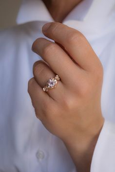 a woman's hand wearing a gold ring with two diamonds on it and a white shirt