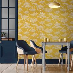 two chairs and a table in front of a yellow wallpapered room with blue doors