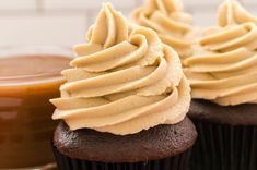 two chocolate cupcakes with frosting and caramel sauce