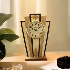 a clock sitting on top of a table next to a potted plant