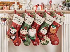 christmas stockings hanging from a mantel in front of a fireplace with santa and snowmen