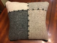 a gray and white pillow sitting on top of a wooden table