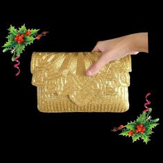 a hand is holding a gold purse with holly and red berries on the side,