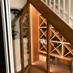 a wine rack under the stairs in a home