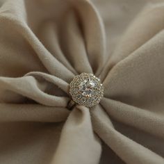 a close up view of a ring on top of a fabric with a diamond center