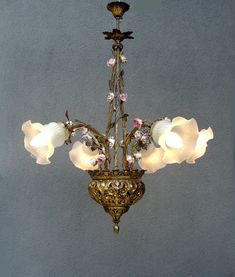 an ornate chandelier with white flowers hanging from it's centerpiece against a gray wall