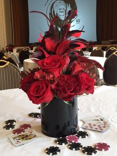 red roses and feathers in a black vase on a white table cloth with matching cards