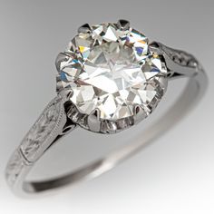 an antique style diamond engagement ring with filigrees on the sides and engraved details