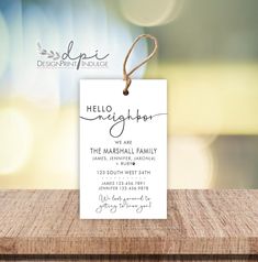 a white card with the words hello neighbor hanging from it's string on a wooden table