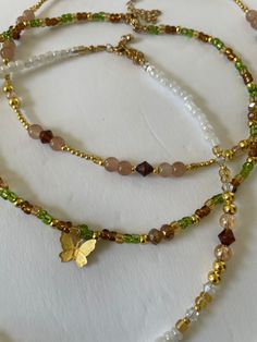 Look beautiful while embracing the spirit of nature with our Forest Fairy Necklaces. A unique blend of hand beaded glass in green, brown and gold, these necklaces are made of glass beads and 14K gold plated beads for lasting wear. Stand tall with nature. Green And Gold Beaded Necklace, Forest Fairy Necklace, Brown Beaded Jewelry, Handmade Gold Nature-inspired Necklace, Handmade Nature-inspired Gold Necklace, Bohemian Gold Beaded Necklace With Spacer Beads, Gold Earthy Beaded Bracelets With Round Beads, Handmade Brown Czech Glass Beads, Unique Gold Beaded Crystal Necklaces