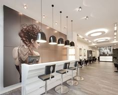 the interior of a hair salon with chairs and lights