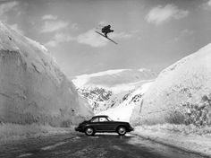 a man flying through the air while riding skis on top of a snow covered mountain