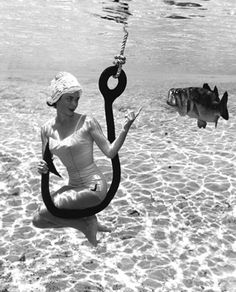 a woman sitting in the water with a fish hook