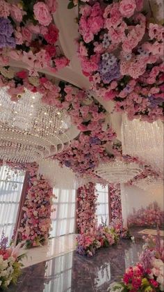 a room filled with lots of pink flowers and chandelier hanging from the ceiling