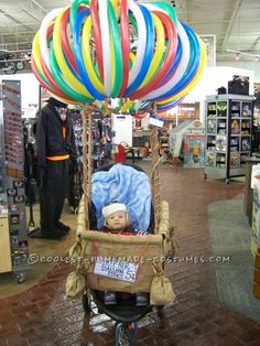 a baby in a stroller with balloons attached to it's back at a store