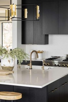 a modern kitchen with black cabinets and white counter tops, gold accents on the faucet