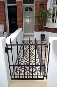 a black and white tiled floor in front of a building with a green door on it