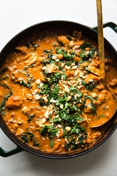 a pan filled with some food and a wooden spoon on top of the pot next to it