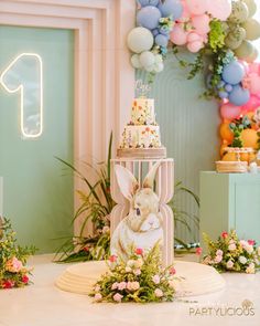 a cake with flowers and bunnies on it in front of a party sign that says one