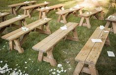 several wooden picnic tables with paper on them in the grass and flowers scattered all around