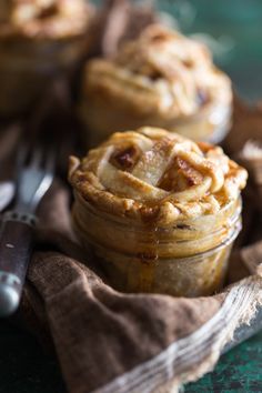 two small pies sitting on top of a cloth next to a fork and knife