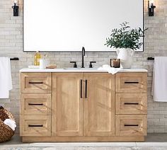 a bathroom vanity with two sinks, mirrors and towels on the rack in front of it