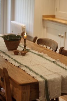 a wooden table topped with a bowl next to a lit candle on top of it