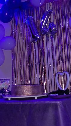 a table topped with a cake and balloons