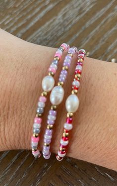 a woman's arm with three bracelets on top of it and beads around the wrist