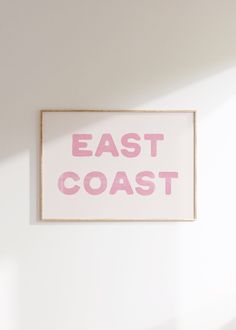 a pink sign that says east coast hanging on the wall in a room with white walls