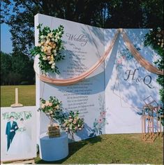 an outdoor wedding ceremony setup with flowers on the wall and pictures hanging from it's sides