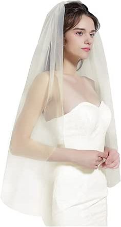 a woman wearing a wedding veil and holding her hand on her hip while standing in front of a white background