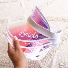 a person holding onto some colorful shoes on a bed with the word bride printed on them