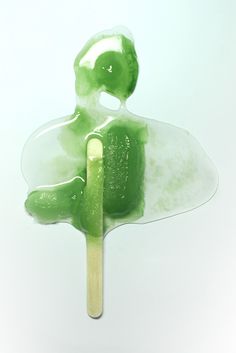 a popsicle with green liquid on it and a toothpick sticking out of it