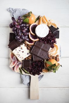 an assortment of fruit and chocolates on a platter with grapes, oranges