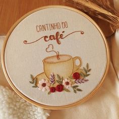 a cross stitch pattern with a coffee cup and flowers on it, next to some yarn