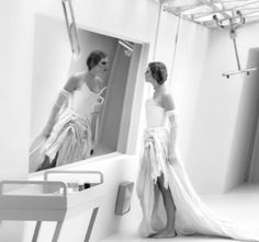 two women in white dresses are looking at each other's reflection in a mirror