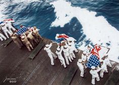 several men in white suits carrying american flags on a ship