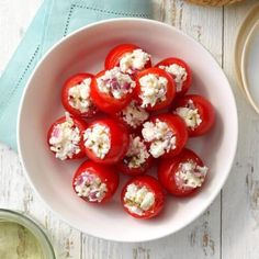 a white bowl filled with tomatoes and feta cheese on top of a wooden table