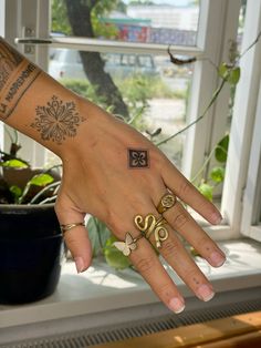 a woman's hand with tattoos on her left arm and two rings in the middle