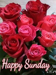 a bouquet of red roses sitting on top of a wooden table with the words happy sunday