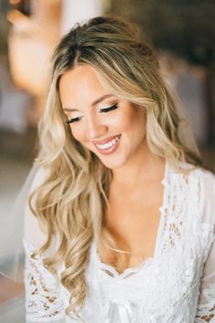 a beautiful blonde woman wearing a white dress and smiling at the camera with her hair pulled back