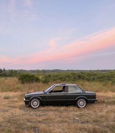 a black car parked on top of a dry grass field