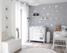 a baby's room decorated in white and gray with polka dots on the wall