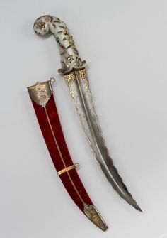 two swords are sitting side by side on a white surface, one is red and the other is gold