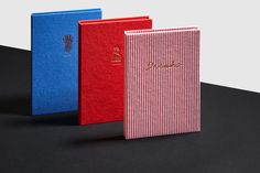 three different colored notebooks sitting next to each other