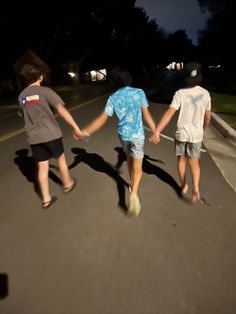 three people walking down the street holding hands