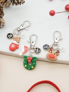 four christmas themed keychains on a white surface with pine cones and other holiday decorations