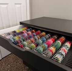 a black piano with lots of colored pencils in it's drawers on the floor