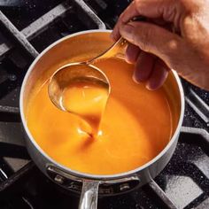 a person spooning liquid from a saucepan on the stove